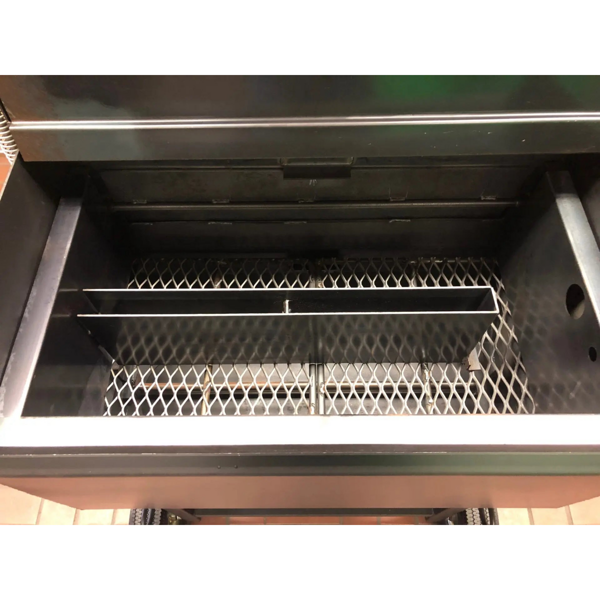 American Barbecue Systems Pit-Boss firebox top-down view showing flat steel floor and rotisserie rod mounts