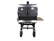 Black barbecue grill on wheels against a beige wall.