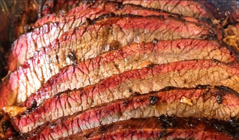 Close-up of perfectly sliced beef brisket showing juicy marbling and charred edges.