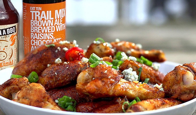 Mighty Mitch's wing sauce glazed chicken wings served with flavorful garnishes and nearby beverages.
