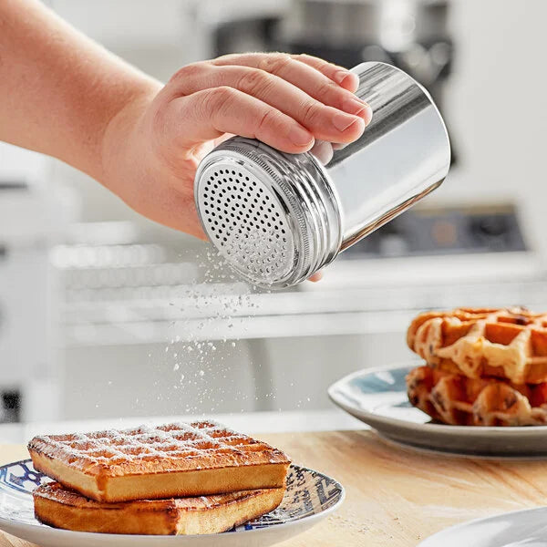 A hand using a 10 oz stainless steel shaker to sprinkle sugar on waffles, showcasing its sleek design and functionality.