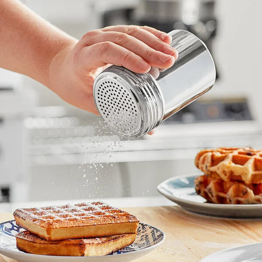 A hand using a 10 oz stainless steel shaker to sprinkle sugar on waffles, showcasing its sleek design and functionality.