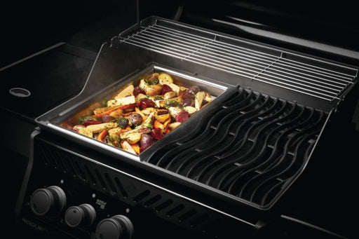 Stainless steel grilling topper on a grill with mixed vegetables cooking.