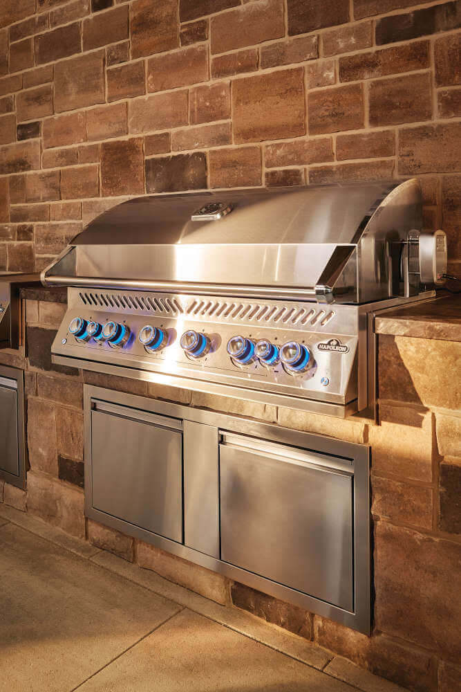 Napoleon built-in propane gas grill with stylish stainless steel design and blue-lit controls.