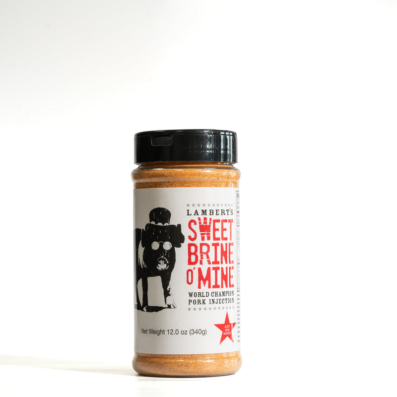 A bottle of Lamberts Sweet Brine O'Mine pork injector seasoning, featuring a white label with red and black text and a black cap, set against a plain white background.