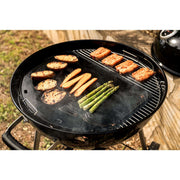 Grilling vegetables and fish on a 22 inch charcoal kettle grill with smoke rising.
