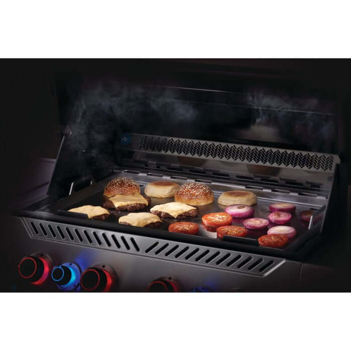 Stainless steel griddle insert for Napoleon grills with burgers and vegetables sizzling on grill.