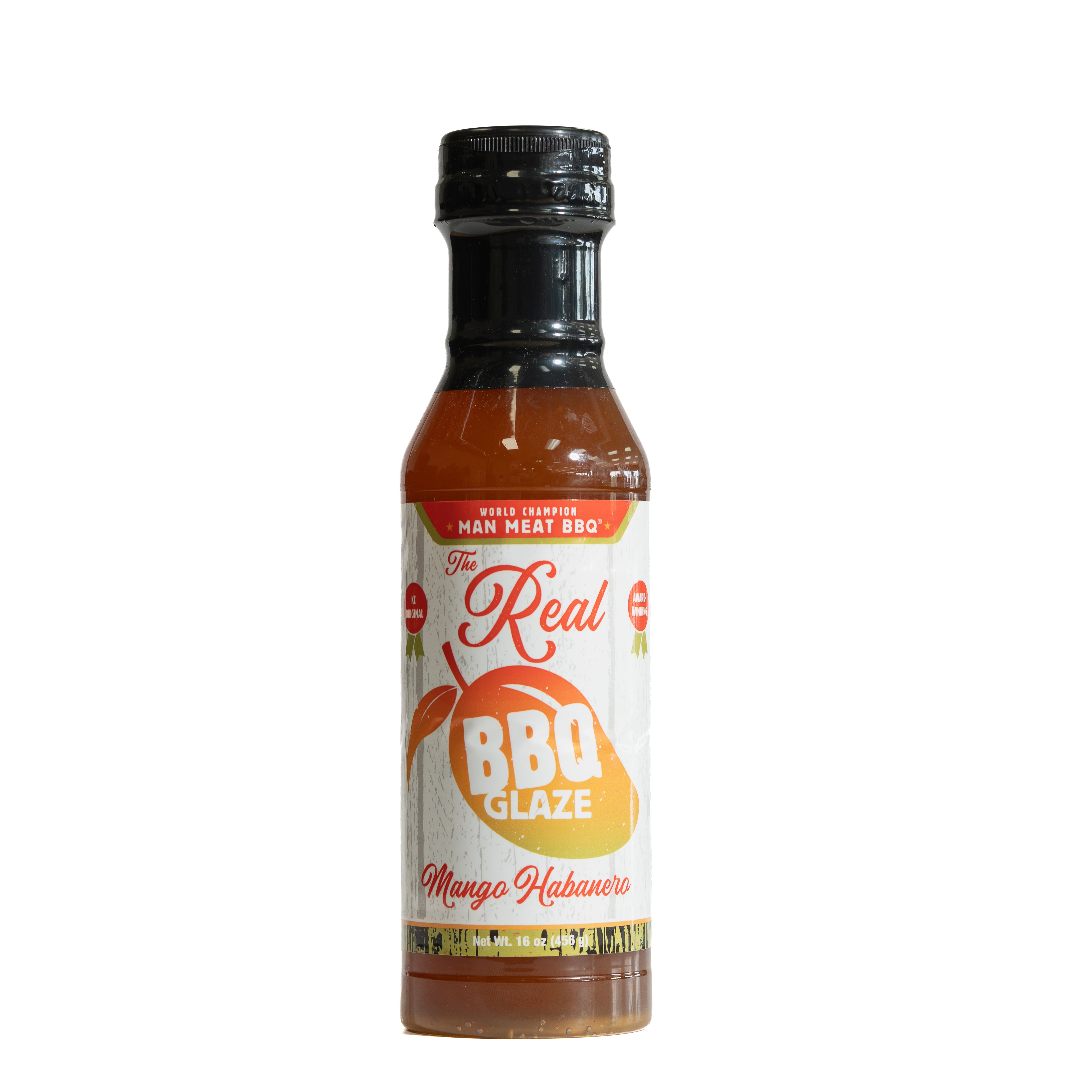 A bottle of 'The Real BBQ Glaze' Mango Habanero sauce on a plain white background. The bottle contains an orange-red sauce and features a white label with red and orange text, a black cap, and a small red 'Made in Mexico' badge.