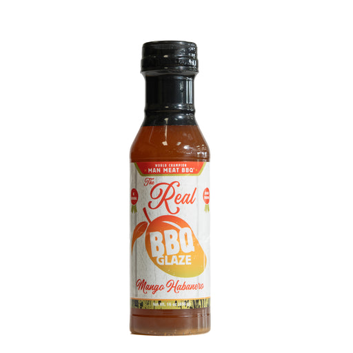 A bottle of 'The Real BBQ Glaze' Mango Habanero sauce on a plain white background. The bottle contains an orange-red sauce and features a white label with red and orange text, a black cap, and a small red 'Made in Mexico' badge.