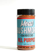 A bottle of Meat Rushmores All Purpose Barbecue seasoning on a white background. The product features a light blue label with white and red lettering, a black plastic cap, and visible reddish-brown seasoning inside and at the bottom of the clear bottle.