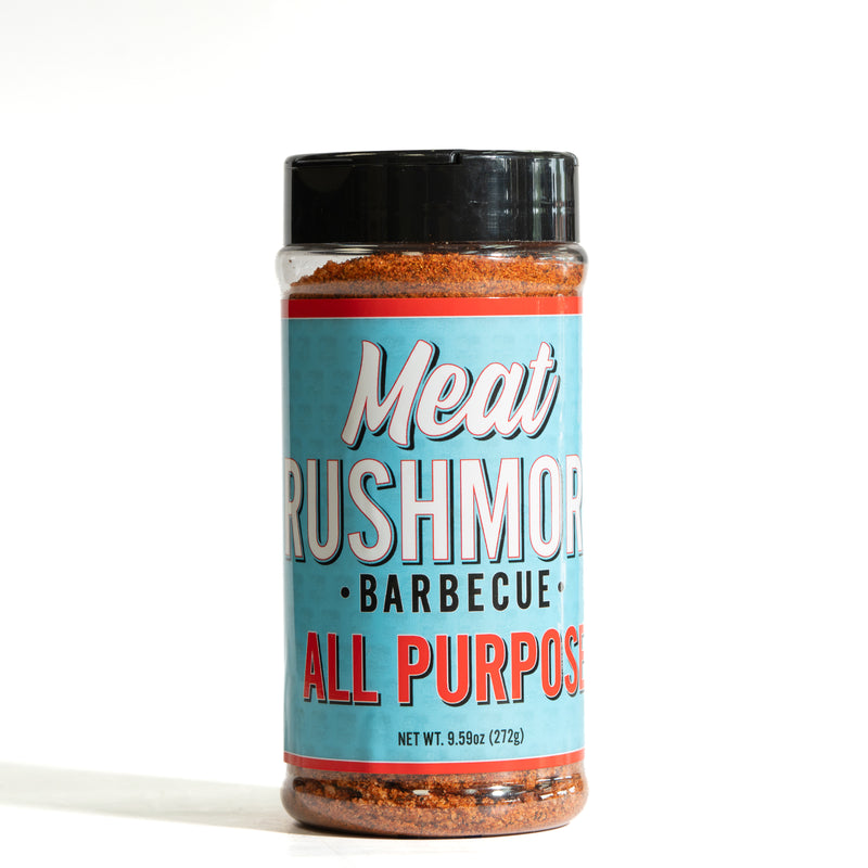 A bottle of Meat Rushmores All Purpose Barbecue seasoning on a white background. The product features a light blue label with white and red lettering, a black plastic cap, and visible reddish-brown seasoning inside and at the bottom of the clear bottle.
