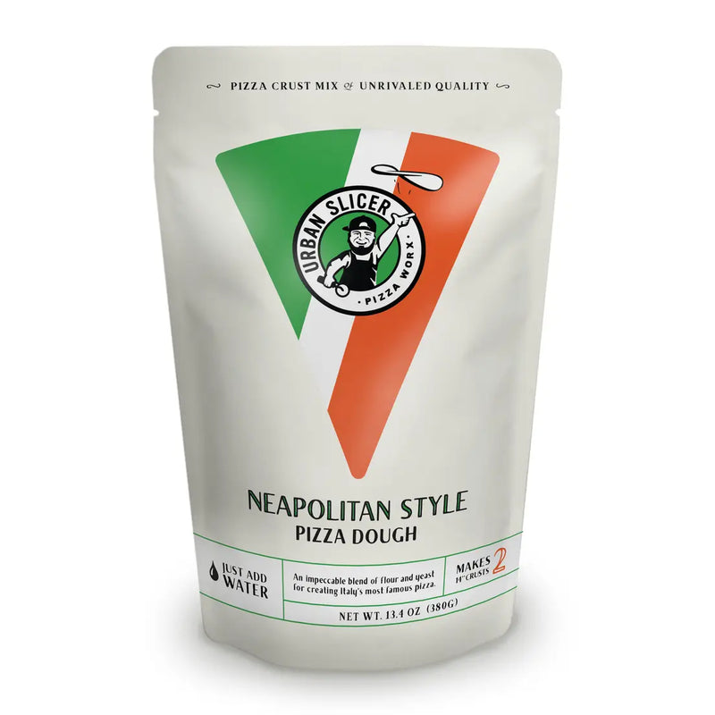 A stand-up pouch of Urban Slicer's Neapolitan Style Pizza Dough on a clean white background. The packaging features a white base with a large green and orange V-shaped graphic resembling the Italian flag, and the circular Urban Slicer logo in the center.